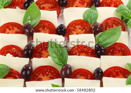 delicious mozzarella and tomato salad (caprese salad) with basil leaves, olive oil and black olives