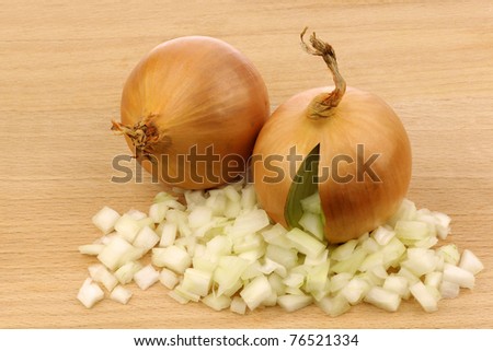 fresh onion with front side opened and already cut pieces coming out on a wooden cutting board