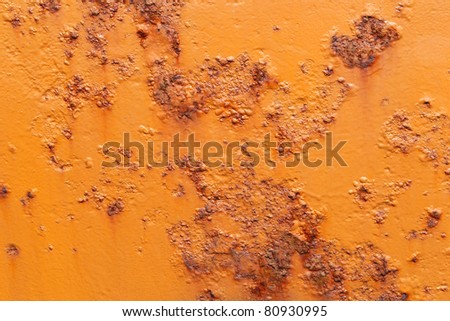 orange painted  hull of a ship with rust coming through