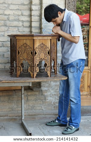 TASHKENT, UZBEKISTAN - MAY 18, 2012: Young furniture maker working on a traditional table on May 18, 2012 in Tashkent, Uzbekistan, Asia
