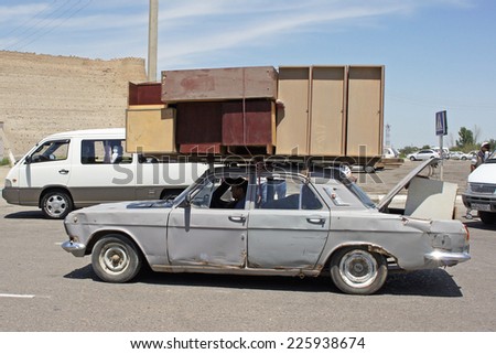 BUKHARA, UZBEKISTAN - MAY 23, 2012: People transporting furniture with an old car on May 23, 2012 in Bukhara, Uzbekistan, Asia