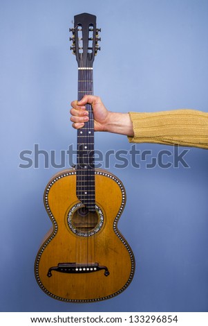 Old guitar held by an outstretched arm