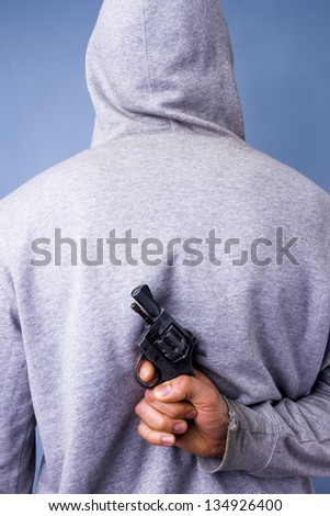 Hooded man hiding gun behind his back
