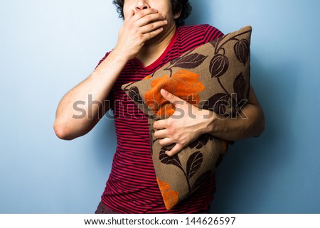Young man clutching cushion while watching scary movie