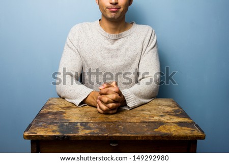 Man is waiting at desk with hands folded