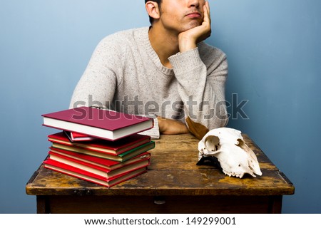 Man with skull and books is trying to think