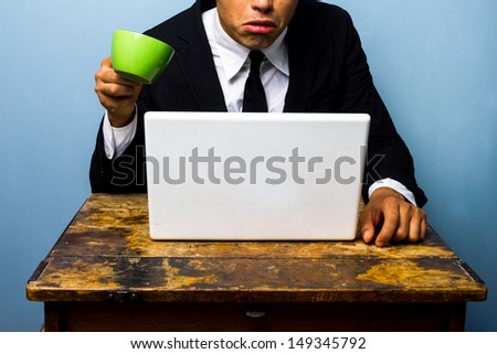 Businessman is surprised and nearly spills coffee on notebook
