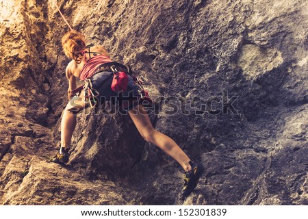 Athletic woman rock climbing at sunset