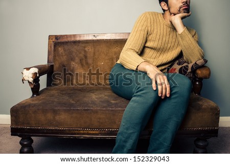 Young man on old sofa is thinking