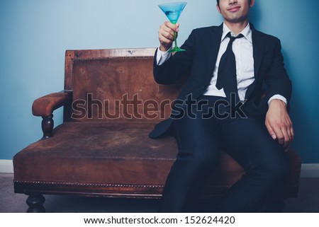 Happy businessman toasting while sitting on old couch