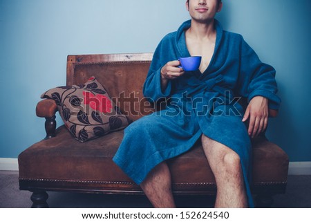 Young man drinking from cup on vintage sofa