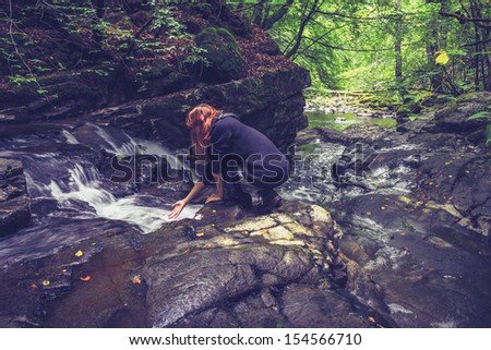 woman washing her hands in mountain stream