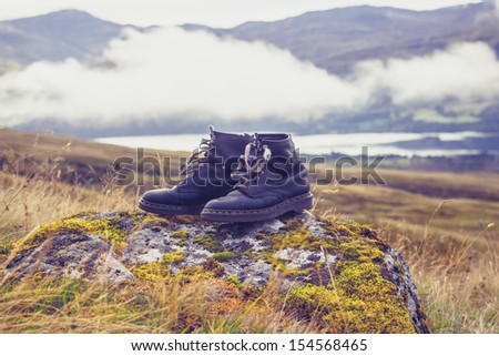 pair of old  black walking boots on a rock in the mountains