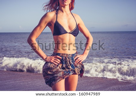 Young woman with toned abs standing on the beach