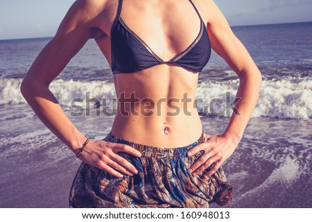 Young woman with toned abs standing on the beach