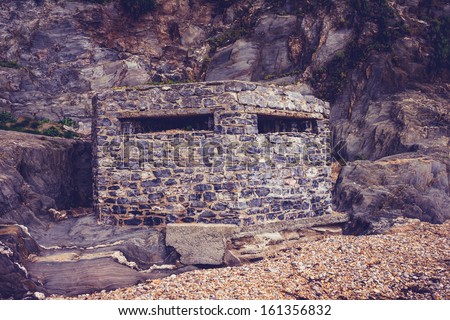 Old world war two bunker on the beach surrounded by rocks