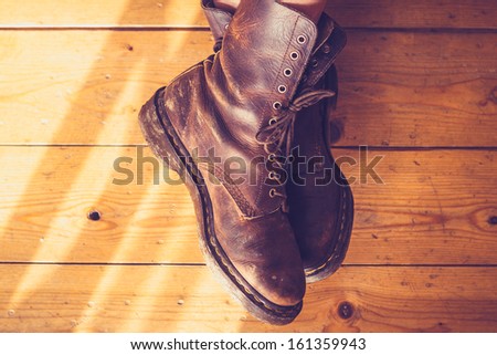 Woman\'s feet in leather boots on wooden floor