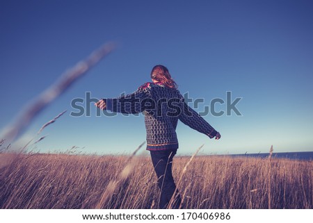 Young Woman Spinning Around In Meadow By The Sea