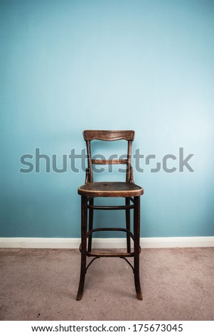 A High antique wooden chair against a blue wall