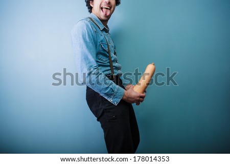 Happy young farmer is showing off his big long butternut squash