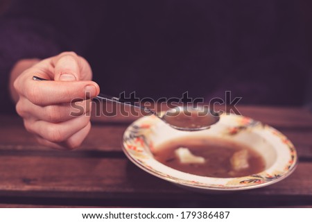 Closeup on a woman\'s hand holding a spoon with soup