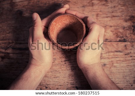 Two hands are holding a leather dice cup at a table