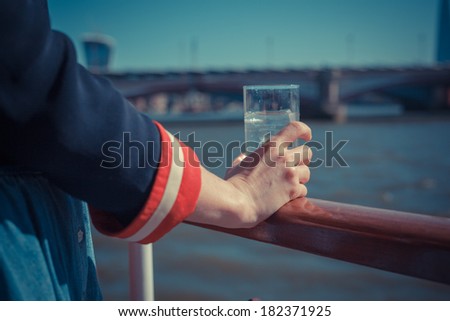 A young woman is on a boat and holding a glass of water