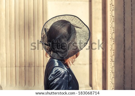 Young woman wearing a hat is walking and looking at an old building