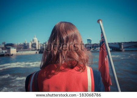 A young woman in a sailor outfit is relaxing on a boat on the Thames in London, England