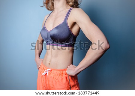Fit young woman with toned abs standing in a dominant pose