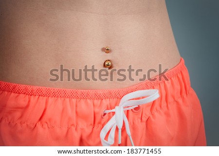 A fit young woman with a toned belly is wearing pink workout shorts