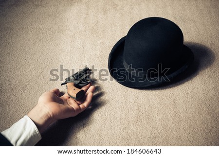 A man is lying dead on the floor with his hat and his revolver