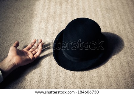 A man is lying dead on the floor with his hat next to him