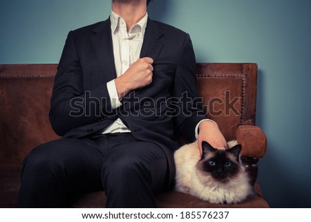 A young man is sitting with his cat on an old sofa