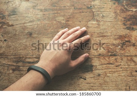 Hand on wood table wearing a fitness tracking armband