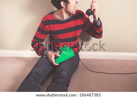 Angry young man is screaming at the telephone