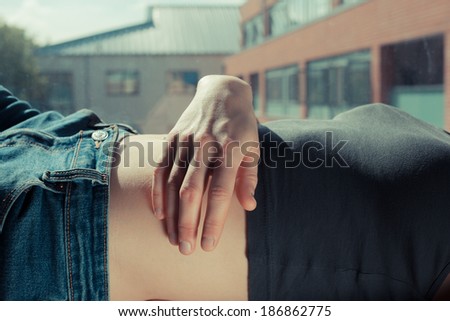 Closeup on a woman\'s hand and stomach as she is relaxing by a window