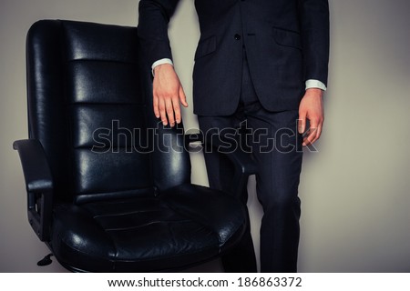 Businessman is standing by a large director\'s chair