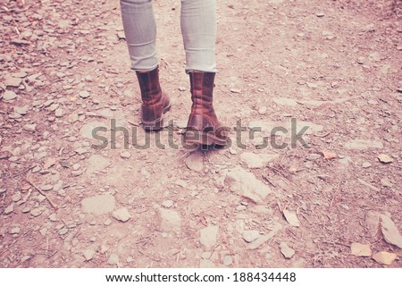 Close up on a young woman\'s feet as she is walking on rocky terrain in the forest