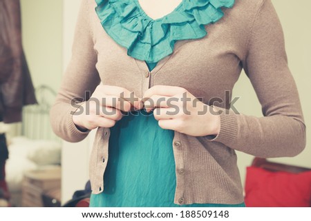 A young woman is buttoning her blouse