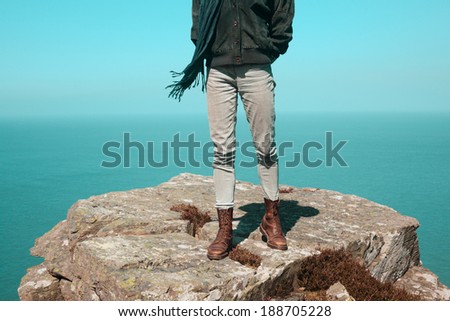 Young woman is standing on a cliff by the sea