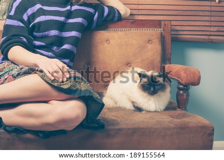 A young woman is sitting on a sofa with her cat