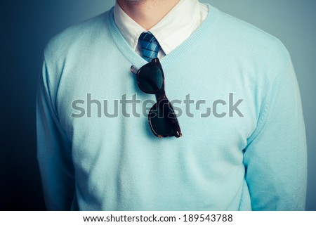 A smartly dressed young man with a pair of sunglasses