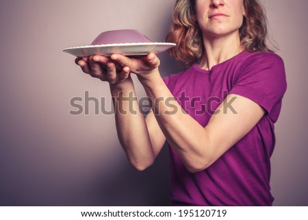 A young woman in a purple top is presenting a plate of jelly