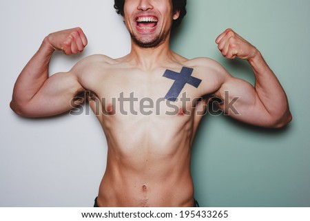 A young athletic man with a tattoo is flexing his muscles against a dual colored background