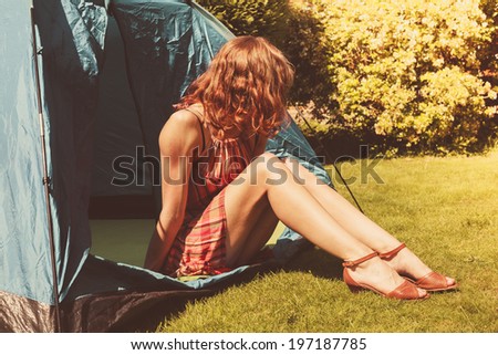 A young woman is sitting in a tent on a summer\'s day