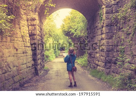 A young woman is lost in a forest below a railway bridge and is studying a map