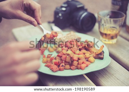 A young woman is eating at a barbecue outside in the evening