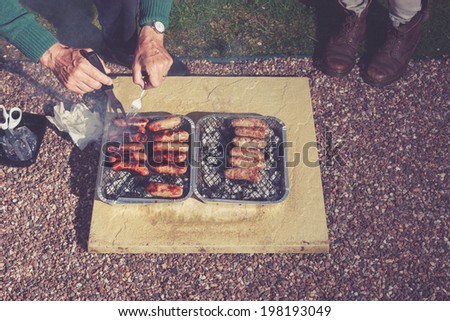 Two people are cooking meat on a barbecue at night