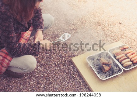 A young woman is cooking meat on a barbecue